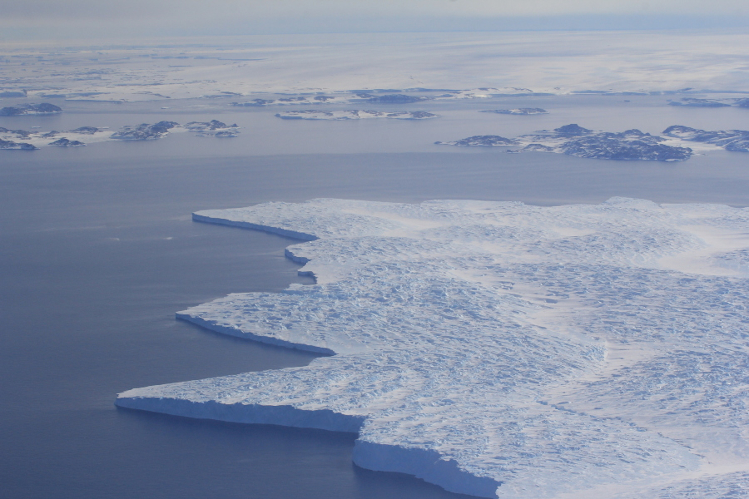 Langue glaciaire flottant sur la mer, près de la base australienne de Casey en Antarctique (décembre 2014). A l'arrière-plan, on distingue quelques îles et la calotte antarctique. © Bruno Jourdain / Ipev / IGE / CNRS Photothèque
