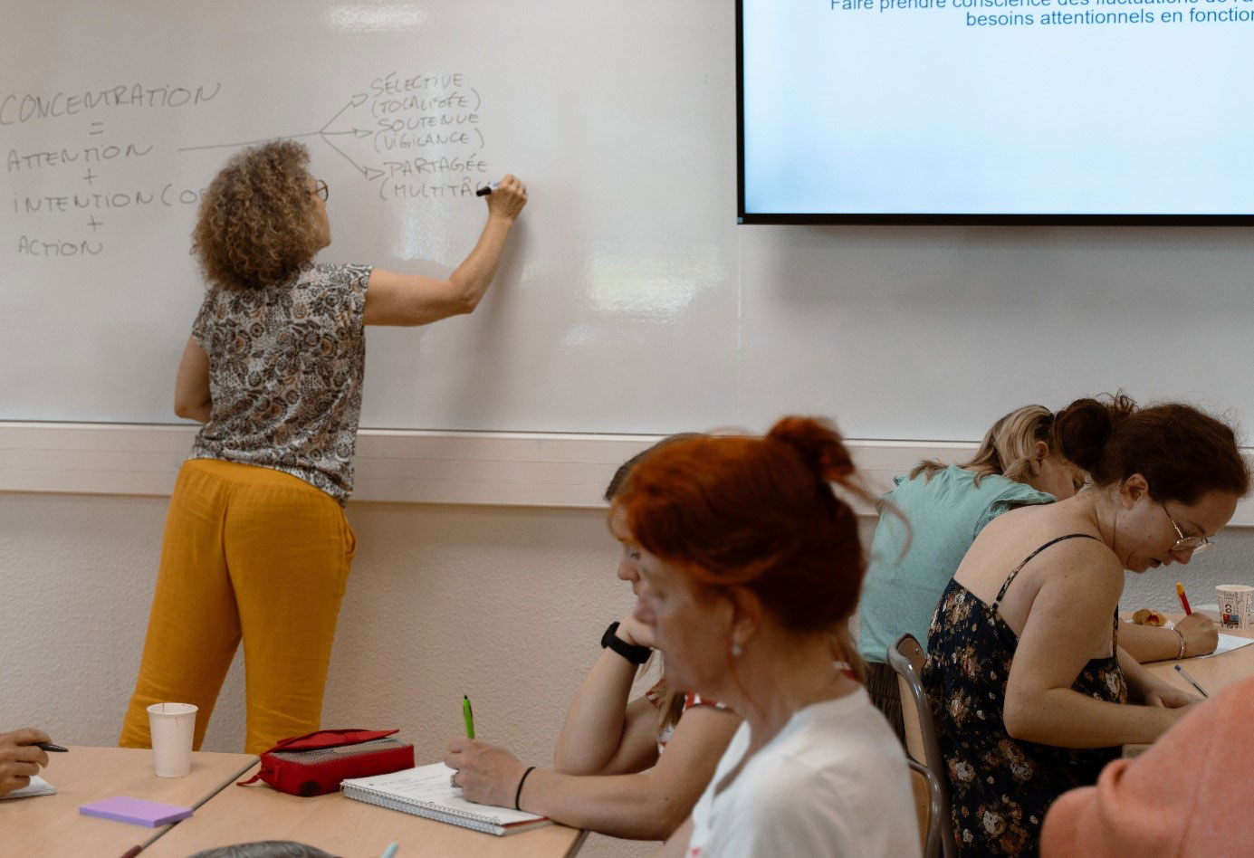Photo d'une enseignante qui écrit qur un tableau blanc